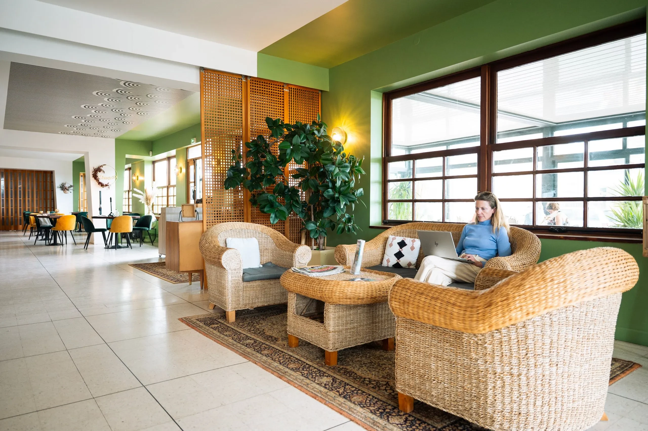 Femme travaillant sur ordinateur dans salon chaleureux - Hébergement Palavas-les-Flots - Hôtel du Midi Palavas