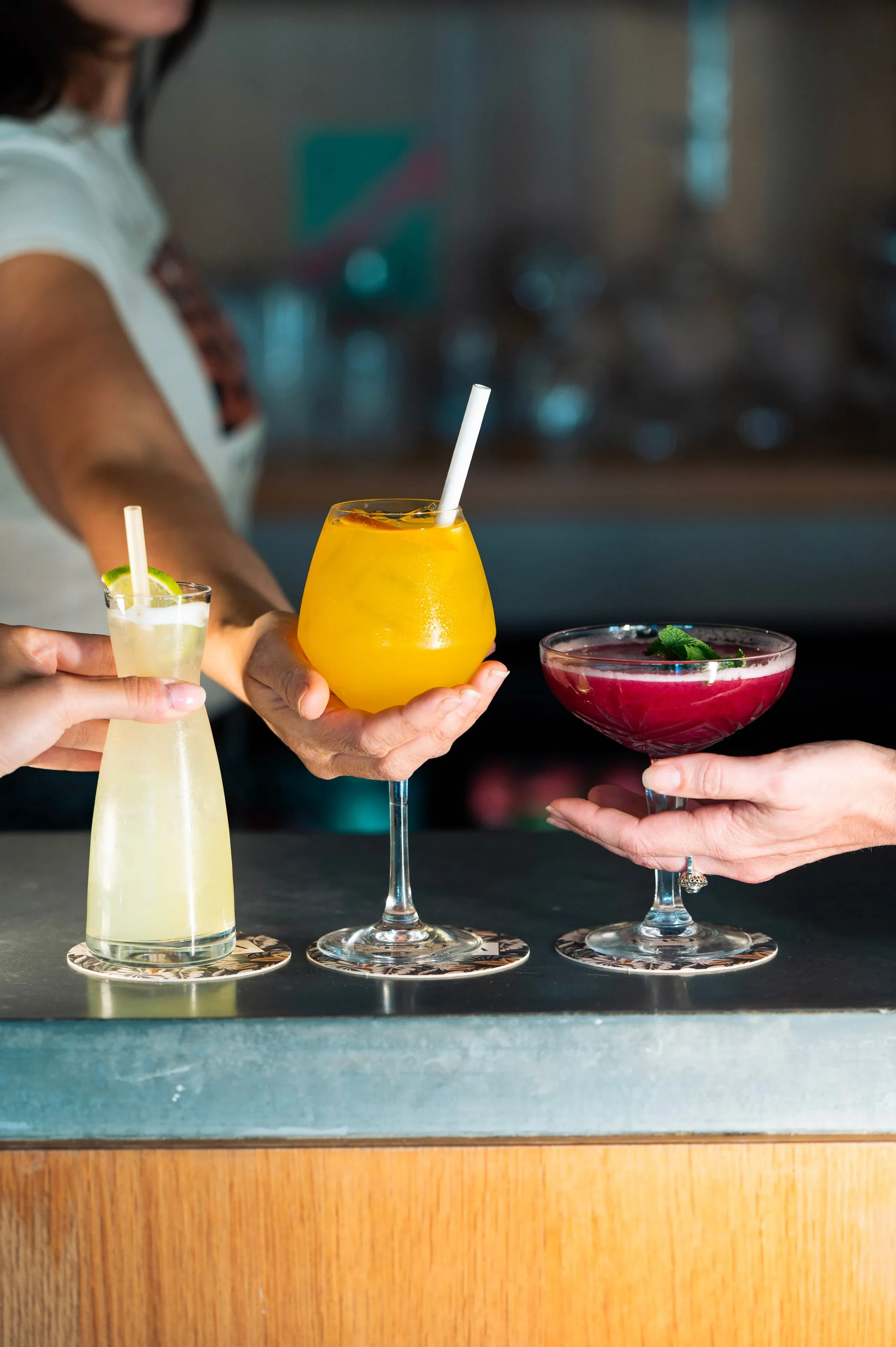 Trois cocktails colorés sur un bar.