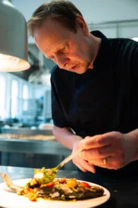 Chef cuisine un plat gastronomique dans une cuisine.