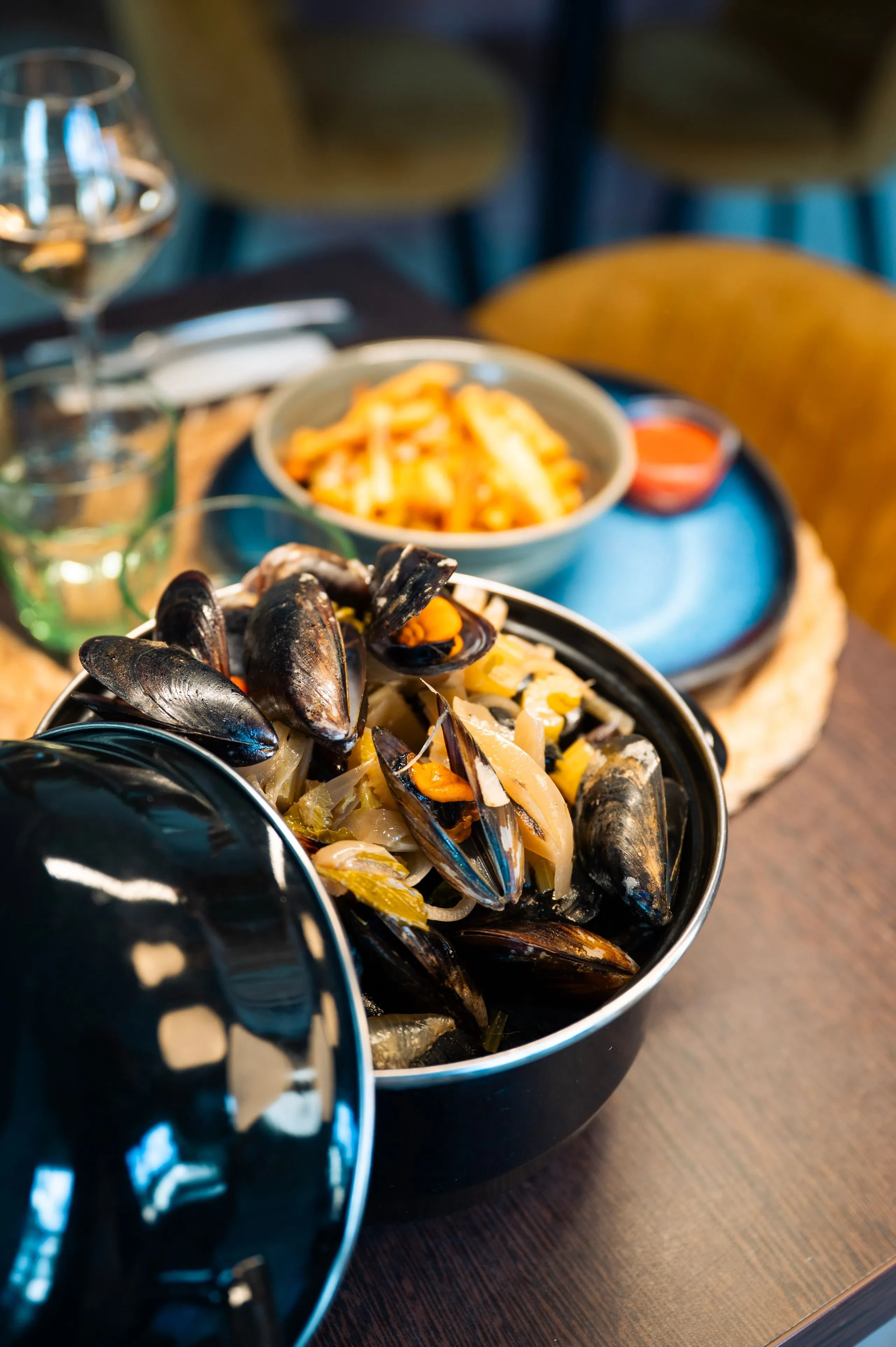 Moules et frites servies avec sauce et vin.