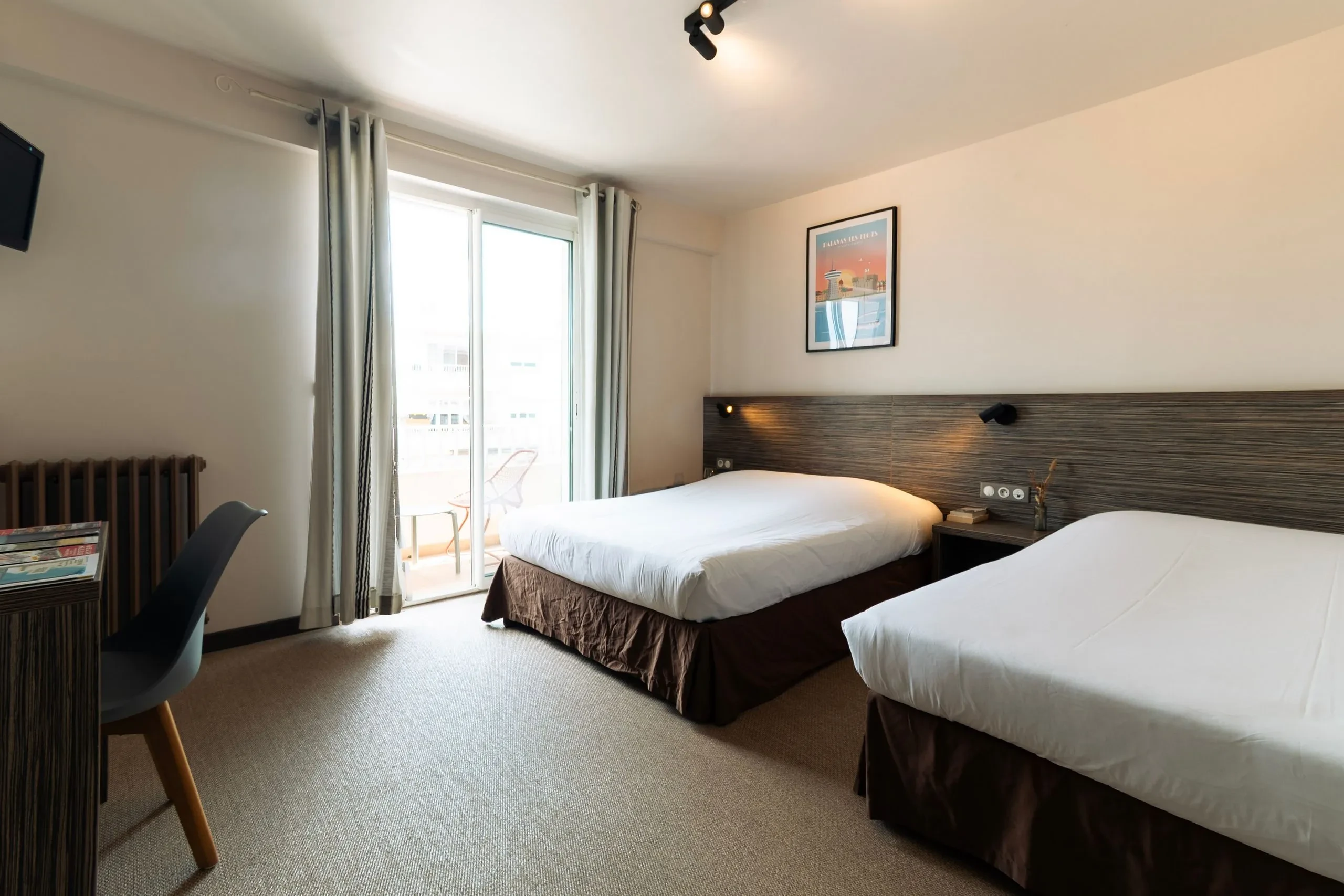 Chambre d'hôtel avec deux lits, balcon visible.