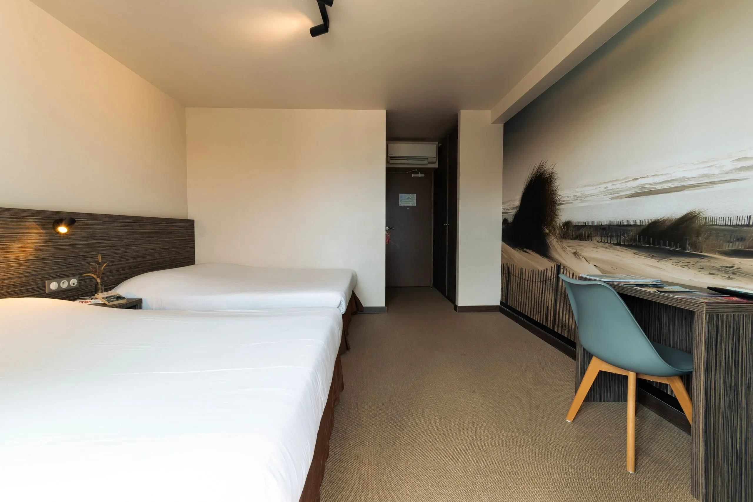 Chambre d'hôtel avec deux lits et mur décoratif.