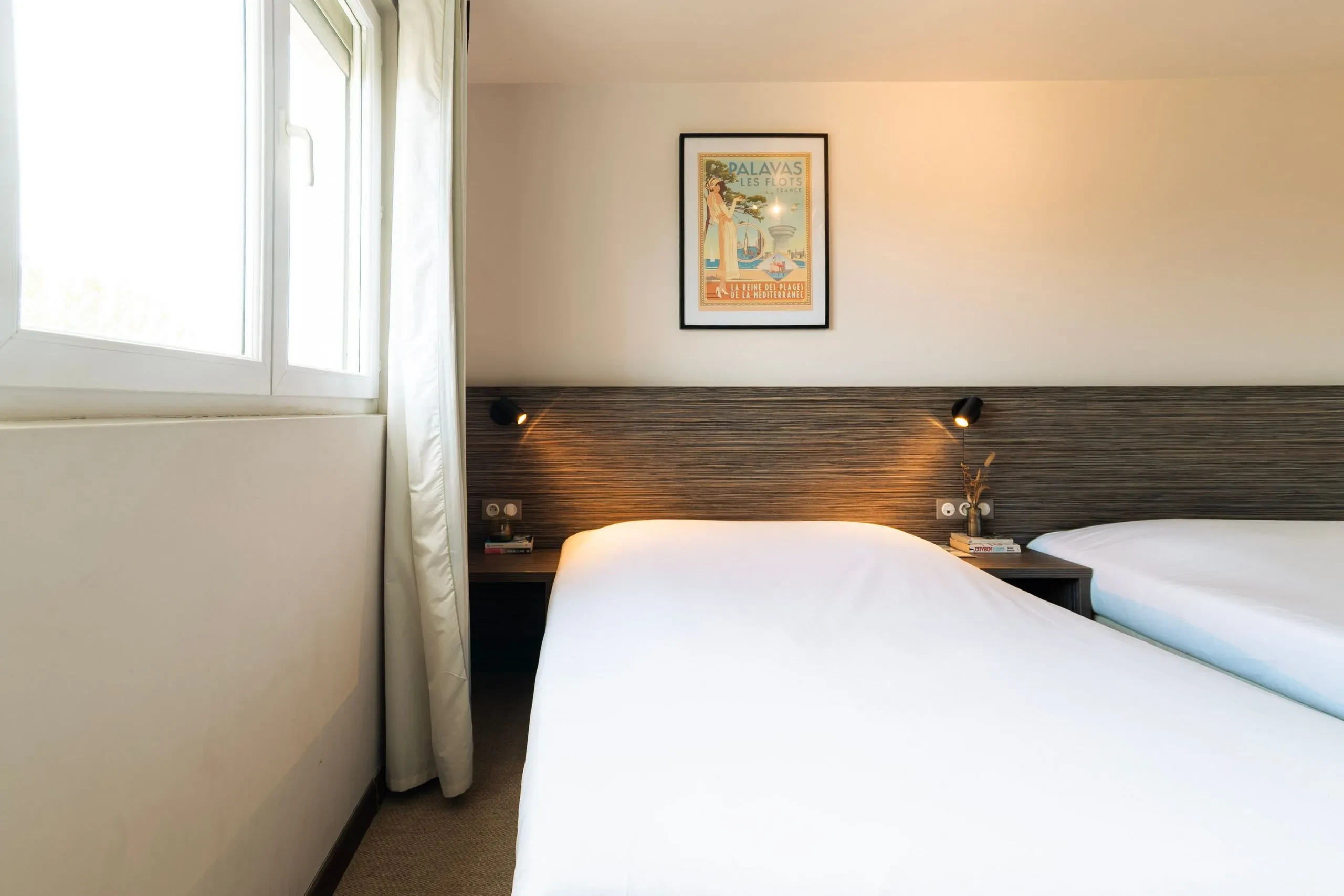 Chambre avec deux lits et fenêtre lumineuse.