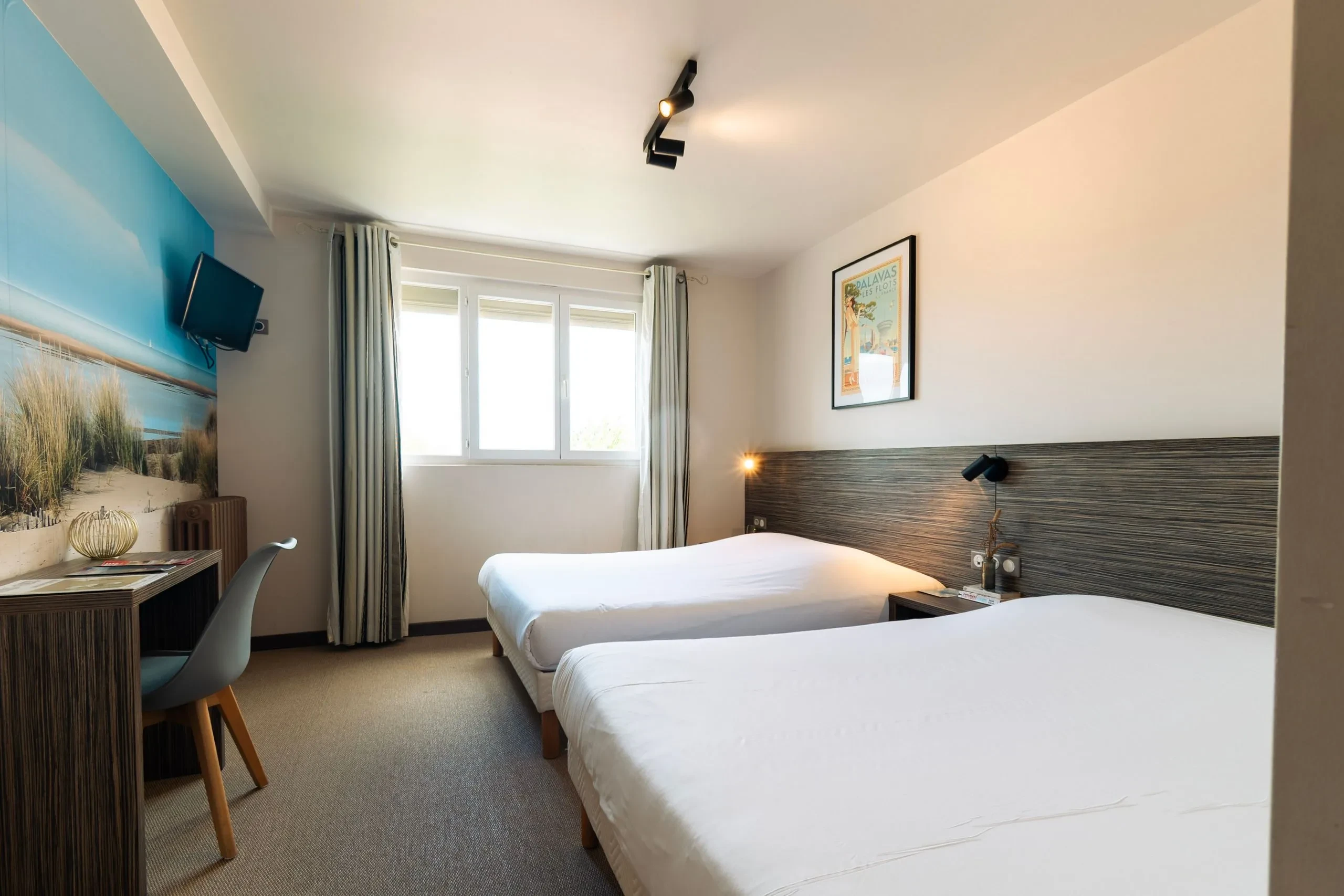 Chambre d'hôtel avec deux lits et bureau.