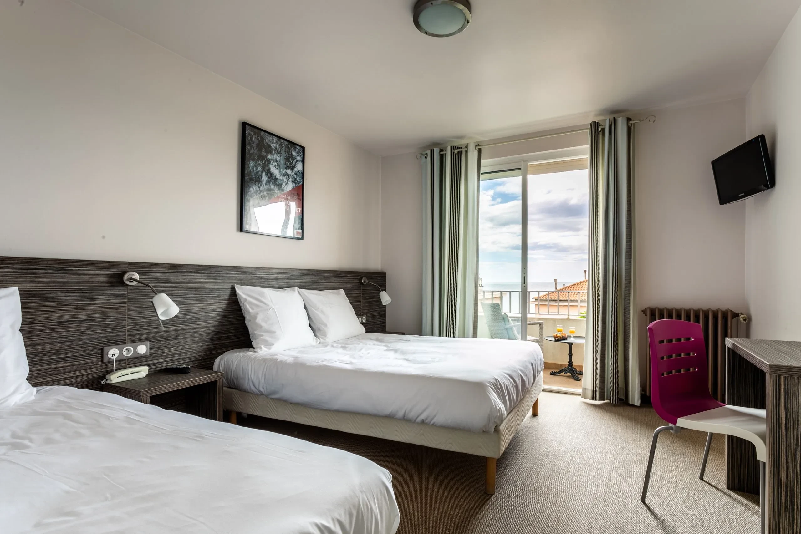 Chambre d'hôtel moderne avec balcon et vue.