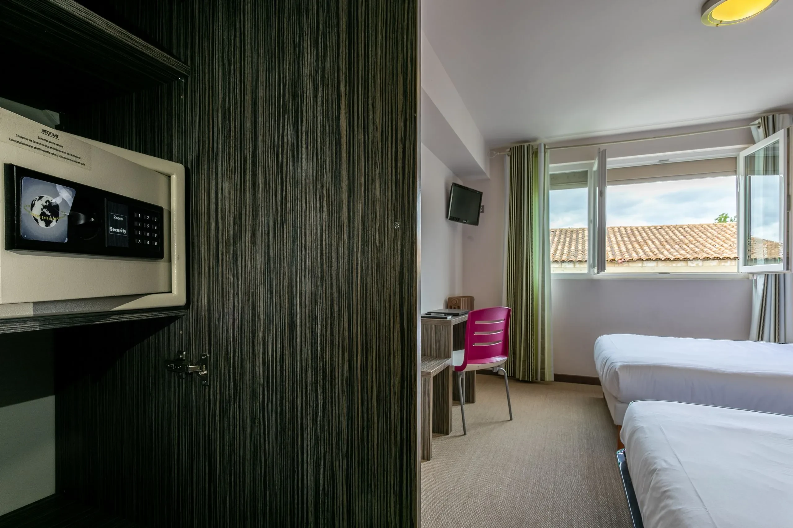 Chambre d'hôtel avec coffre-fort et lits.