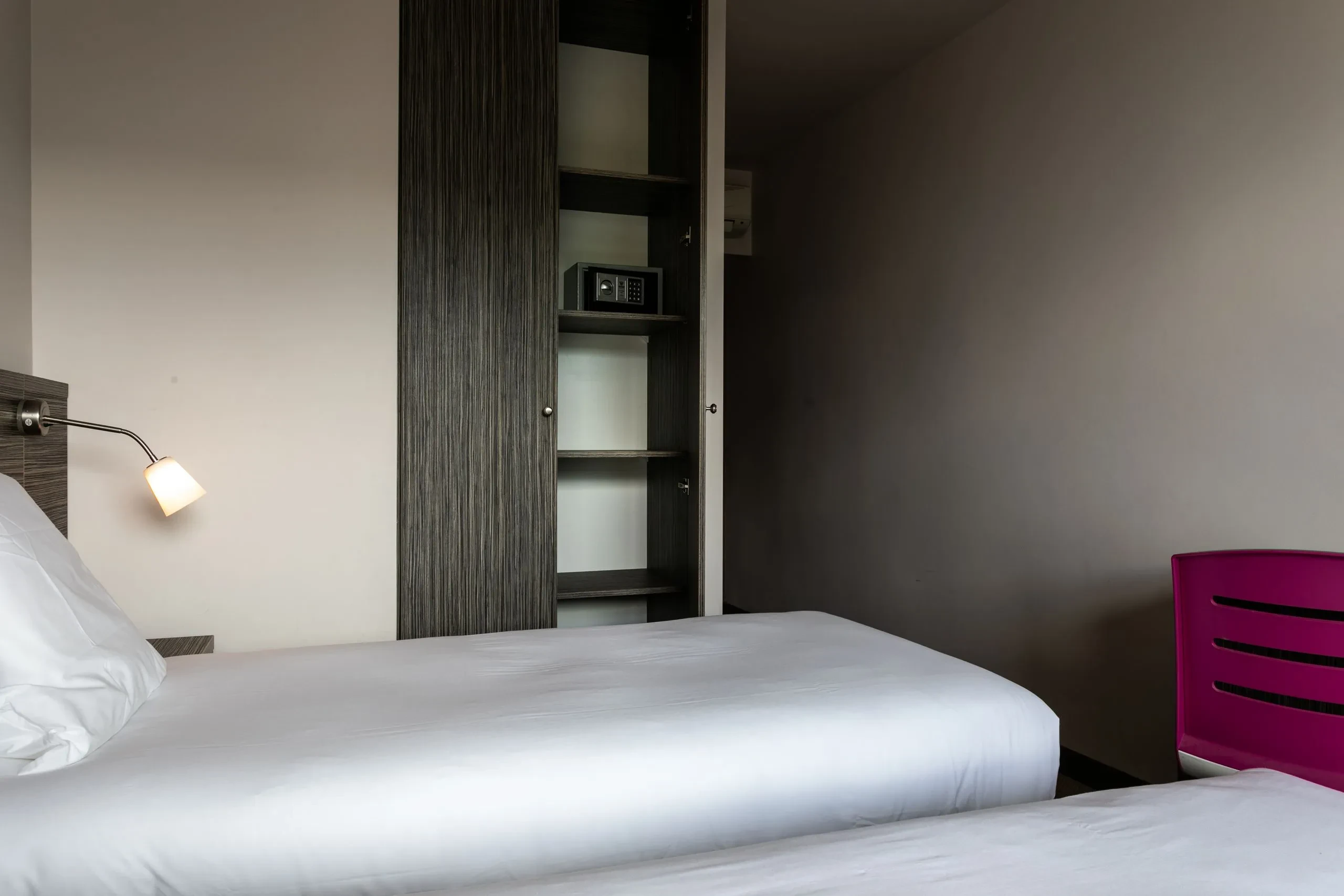 Chambre d'hôtel avec lit et placard ouverts.